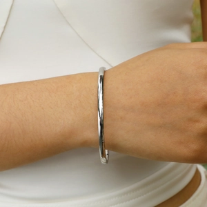 Close-up of minimalist silver stainless steel bangle with polished mirror finish on wrist