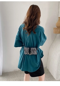 Close-up of zebra pattern belt bag with metal ring detail on green shirt model