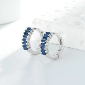 Vue détaillée des boucles d'oreilles huggie en argent S925 serties de zircons bleu marine