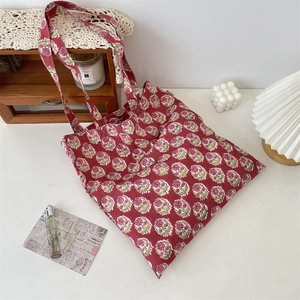 Detail of red floral canvas tote bag with woven label and vintage aesthetic