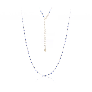 Detailed view of a gold chain necklace with blue beads and a teardrop pendant