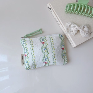 Gros plan d'une broderie florale sur une pochette en coton blanc avec étiquette latérale