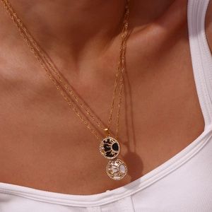 Dettaglio della collana in acciaio dorato con ciondolo sole e luna sulla modella
