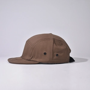 Detail view of brown canvas camper cap featuring metal eyelets and reinforced stitching