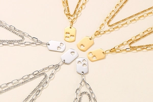 Detail of layered gold and silver necklaces with hollow heart square pendants