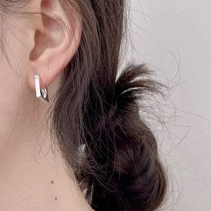 Close-up of minimalist silver square hoop earring worn on earlobe for a modern look