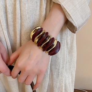 Macro shot of wide-band geometric bangle with burgundy resin and gold metal segments