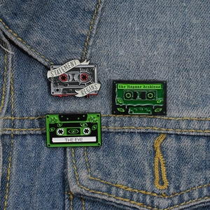 Lot de pins émaillés Magnus Archives rétro avec cassettes vertes sur veste en jean