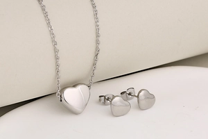 Minimalist silver heart jewelry set featuring necklace and stud earrings on geometric base