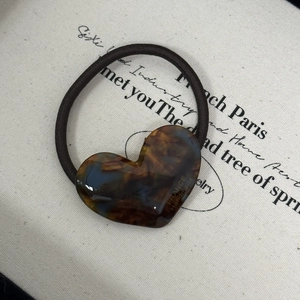 Detail of a brown tortoiseshell heart-shaped acetate hair tie with France Handmade text