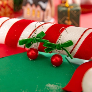 Détail macro des boucles d'oreilles de Noël avec nœud en velours vert et perles rouges