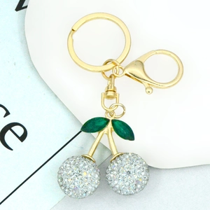 Detailed view of a gold cherry keychain featuring silver rhinestones and green leaves
