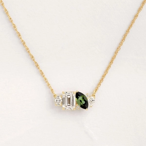 Golden necklace featuring emerald-cut clear stone and marquise-cut green gemstone charms