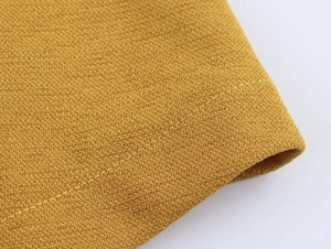 Dettaglio macro della trama in maglia gialla di qualità e delle cuciture del vestito