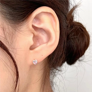 Detail of pink heart-shaped zircon stud earring worn by a model in silver setting