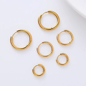 Set of three pairs of minimalist golden hoop earrings in various sizes on white background