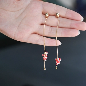 Détail de boucles d'oreilles de Noël asymétriques avec figurines de Père Noël peintes