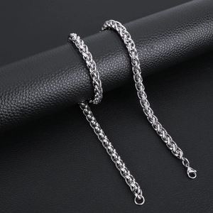 Macro shot of silver wheat chain necklace with lobster clasp on black leather background