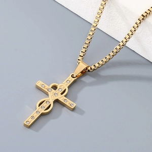 Detail view of a golden cross pendant with heart engraving and small white crystals