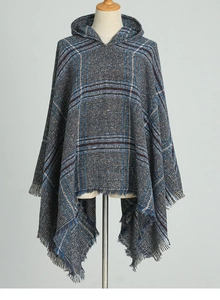 Détail du poncho à capuche à carreaux montrant la texture tissée gris-bleu et les franges