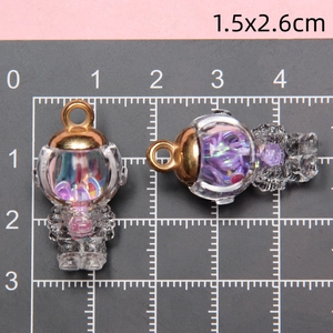 Detailed view of two astronaut glass pendants with purple sequins and measurement scale