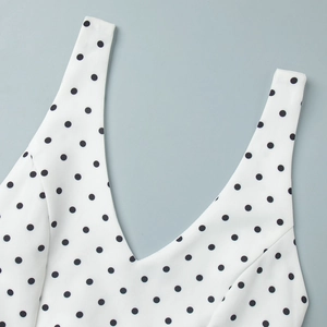 Détail du décolleté en V profond d'un haut en mousseline blanche à pois noirs élégant