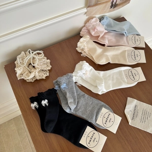 Detail shot of multi-colored cotton socks with 3D bows displayed on a wooden table