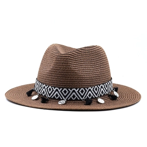 Détail d'un chapeau de paille avec ruban géométrique, glands noirs et pièces argent