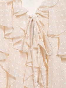 Detail of beige polka dot chiffon blouse featuring ruffled trim and a bow tie neckline
