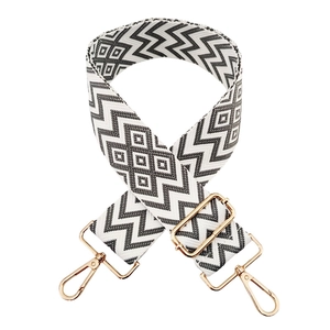 Detail of adjustable black and white geometric bag strap with gold lobster clasps
