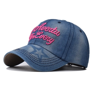 Détail de face d'une casquette en denim bleu délavé avec broderie rose et motif d'étoile
