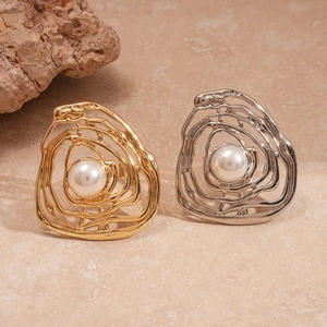 Golden and silver irregular hollow lava rings with imitation pearls on stone background