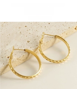 Detail of gold round hoop earrings featuring a hammered geometric texture finish