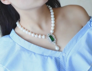 Detail of vintage pearl necklace featuring an emerald pendant with zircon lace edges
