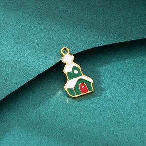 Detail of Christmas house charm with green enamel and gold finish on green paper