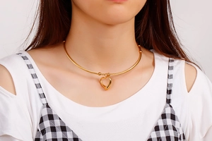 Close-up of a minimalist hollow heart pendant necklace in gold finish on a model