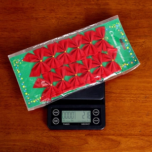 Weight measurement of 12 piece red velvet Christmas tree bow decorations on a digital scale