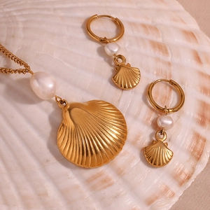 Detail of 18K gold plated shell and pearl jewelry set placed on a natural shell