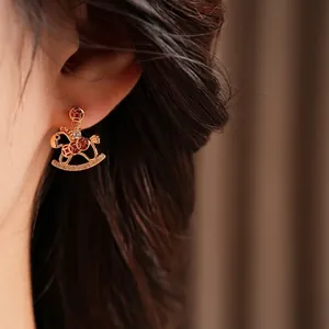 Gold plated rocking horse earrings with red enamel and pavé zircon stones on model