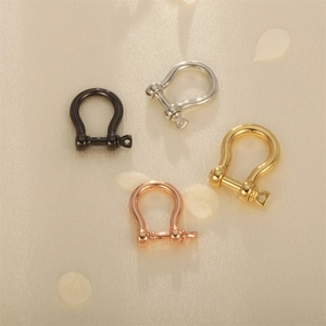 U-förmige Schäckel-Anhänger in Schwarz, Gold, Silber und Roségold auf Stoffhintergrund