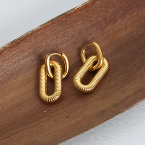 Orecchini ovali placcati oro con design testurizzato su una superficie in legno naturale