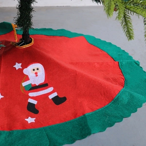 Red Christmas tree skirt with green scalloped edge featuring Santa and stars design