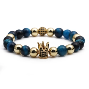 Golden crown bracelet with blue tiger eye stones and micro-pave crystals on white background