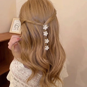 Set of four minimalist white camellia flower hair claws worn in an elegant half-up style