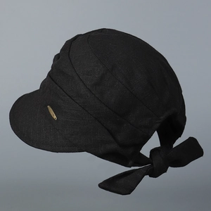 Detail of black cotton linen sun hat with golden logo plate and bow strap design
