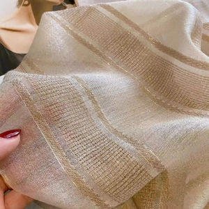 Macro shot of silk wool scarf fabric with delicate gold metallic stripes and texture
