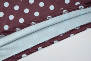 Vue détaillée de l'ourlet à double couture et des pois bleus sur tissu bordeaux