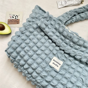 Detailed close-up of blue bubble textured canvas tote bag with a branded woven label