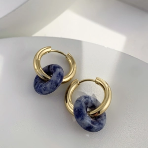 Detailed macro view of 18K gold hoop earrings featuring deep blue natural stone pendants