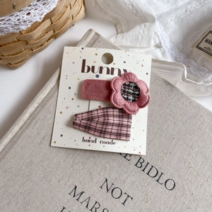 Detail of pink floral plush and checkered fabric hair clips on a gift card display